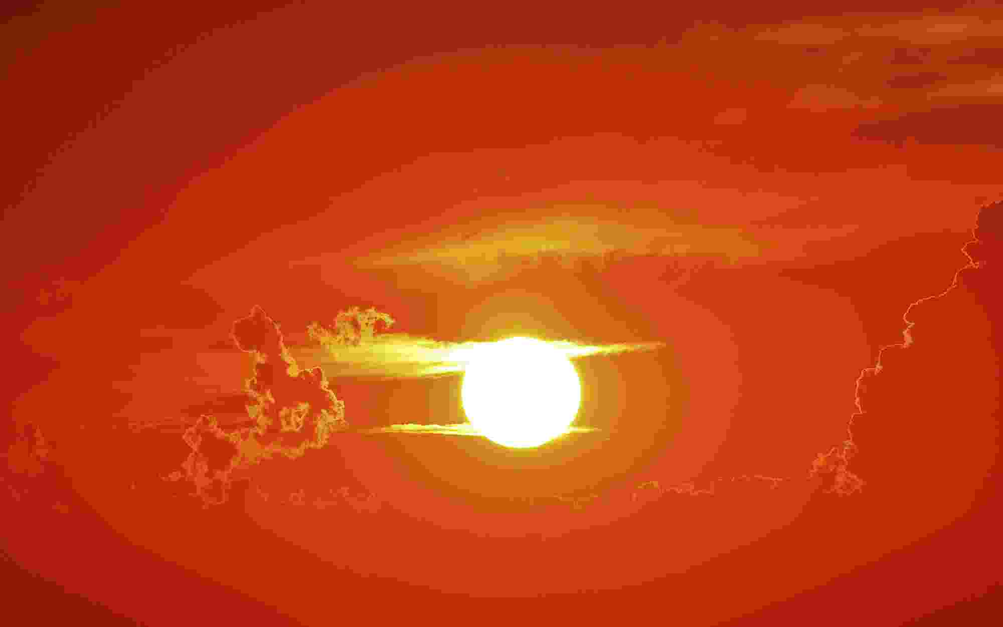 A glowing white sun against a clear, red sky